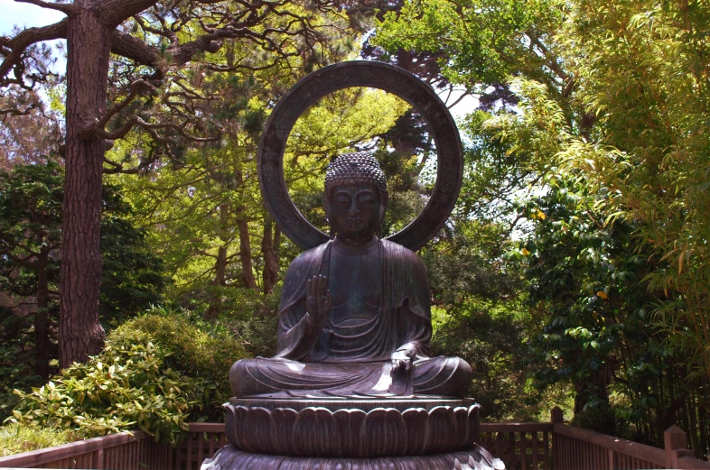 a statue of a sitting buddha surrounded by greenery