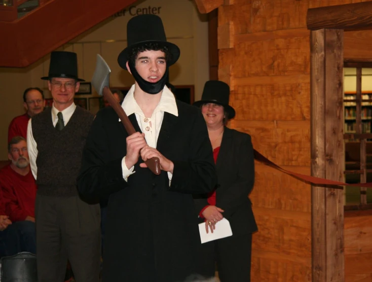 a man in a black suit with a top hat holding a large hammer