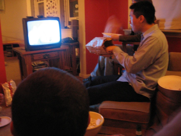 a couple of men sitting in chairs eating pizza