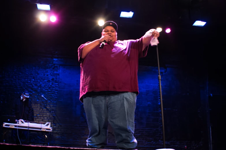 a man standing on a stage and singing into microphones