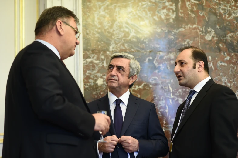 three business men are talking together in front of a painting