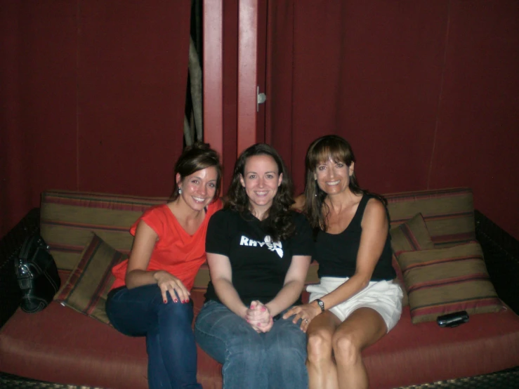 three woman sit on a sofa smiling for the camera