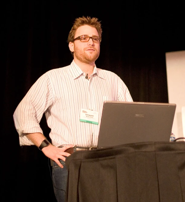 a man in glasses is standing in front of a laptop