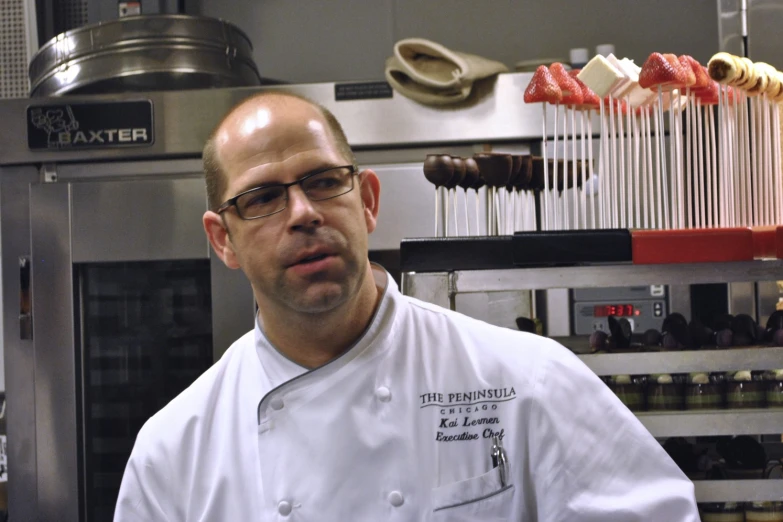 a man wearing glasses standing in front of some food