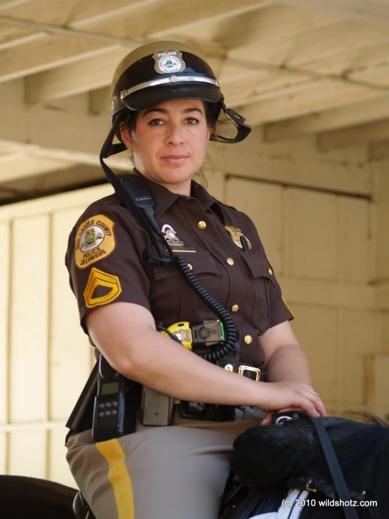 a woman is sitting on the horse wearing a sheriff outfit