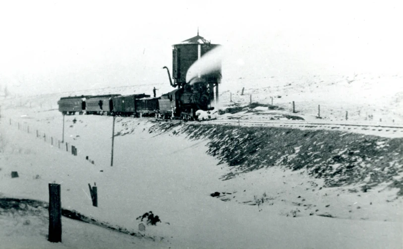 black and white po of train on tracks with mountains in background