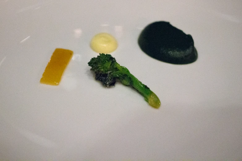 a white plate topped with broccoli, cheese and a piece of fruit