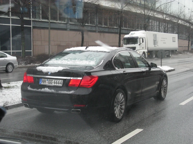 black bmw parked at curb on a wet day