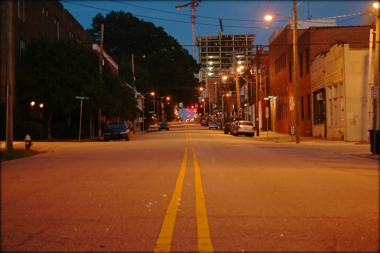 an empty city street with some cars parked in it