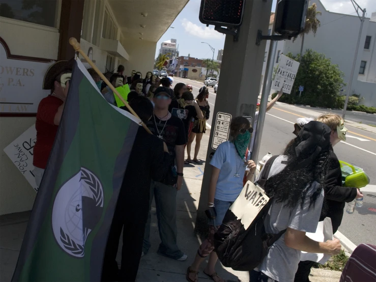 many people standing on the side walk with signs