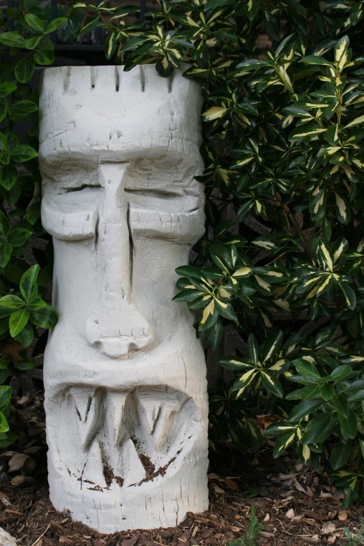 a white statue is shown in front of bushes