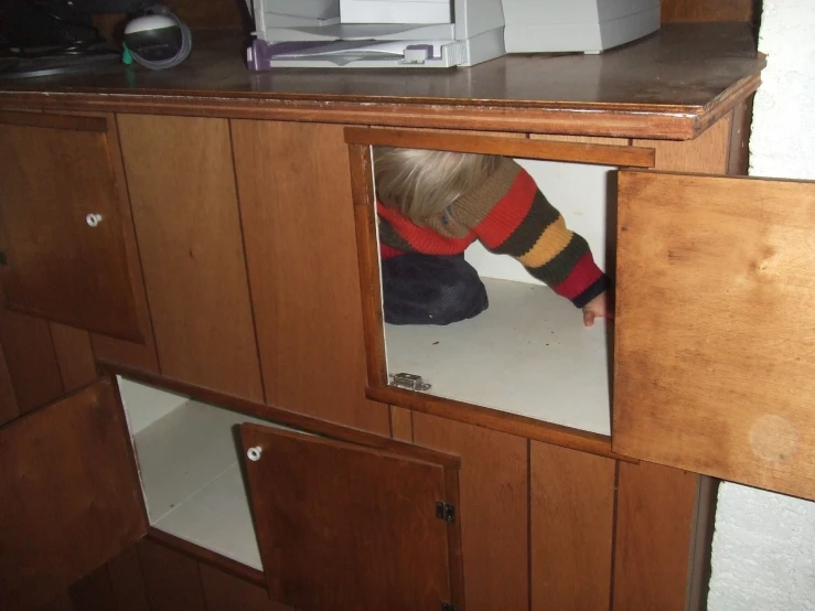 a child is peeking through a cupboard door