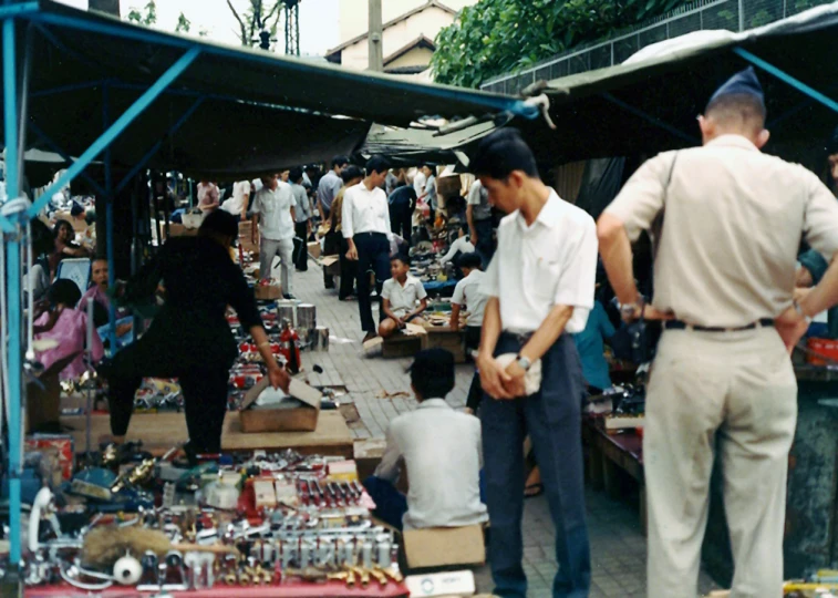 there are many people standing around an outdoor market