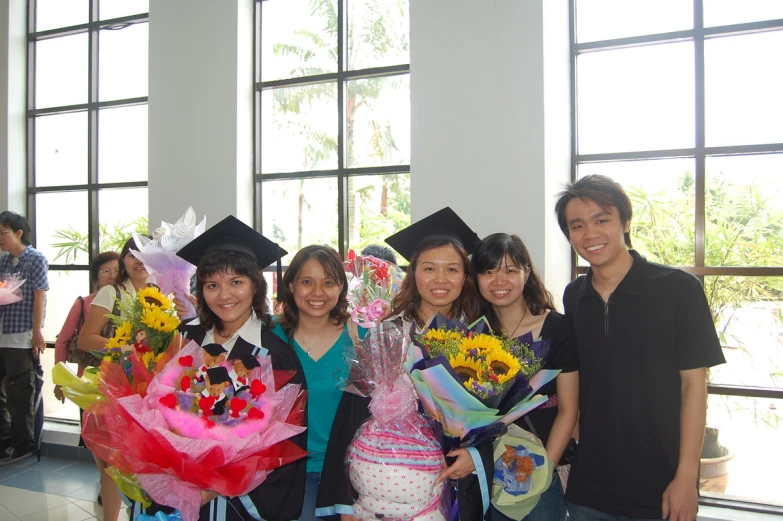 group of students dressed in graduation gowns holding bouquets