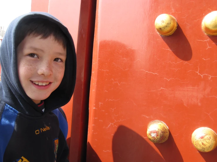 a  in a black and blue jacket standing in front of a large red door