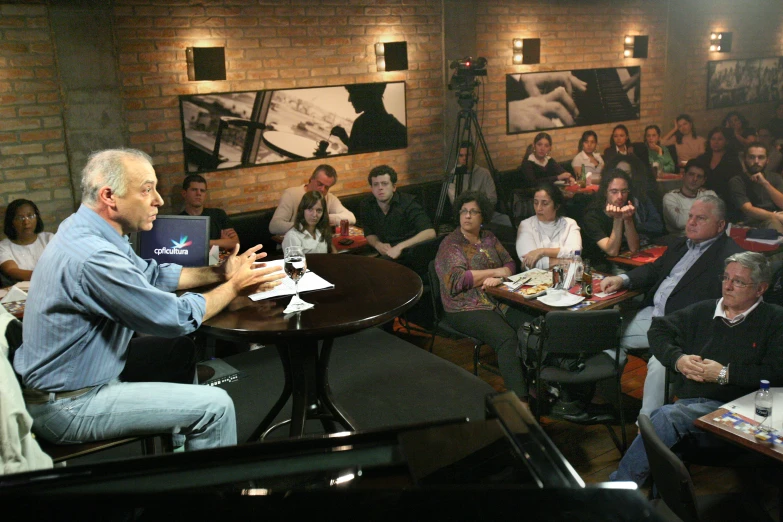 a man standing in a room talking to an audience