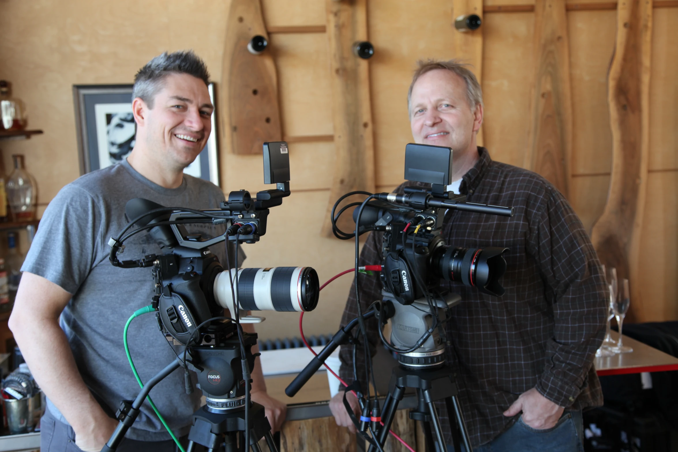 two men standing near each other with camera equipment