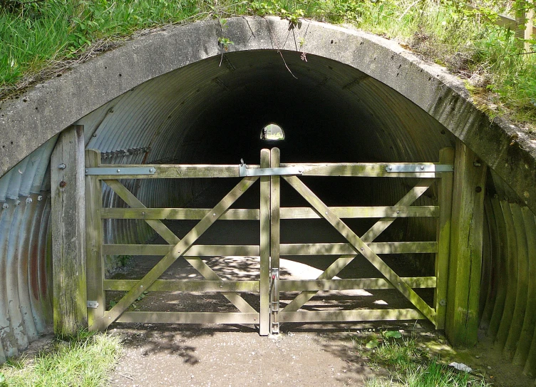 a tunnel entrance with wooden fence and gate