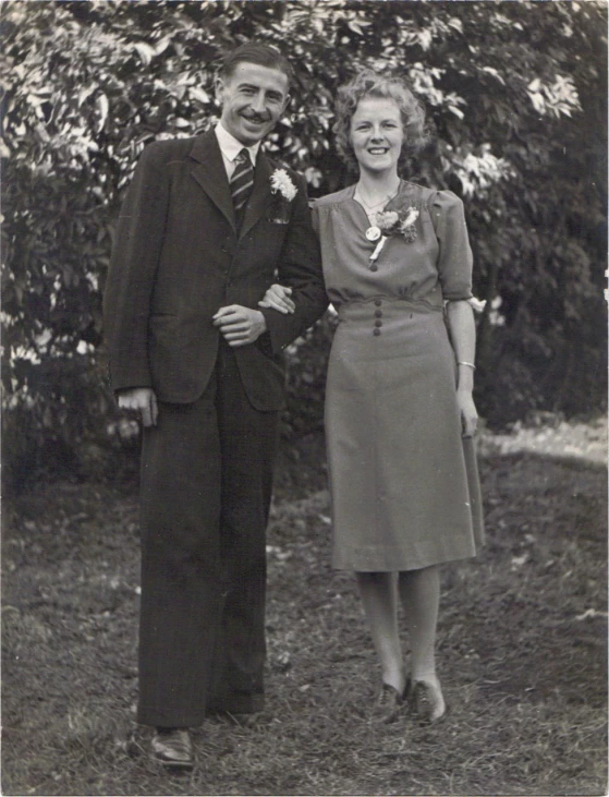 a man and woman standing in front of a tree