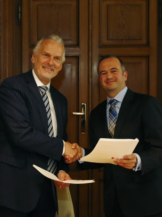 two men shaking hands with paper and papers