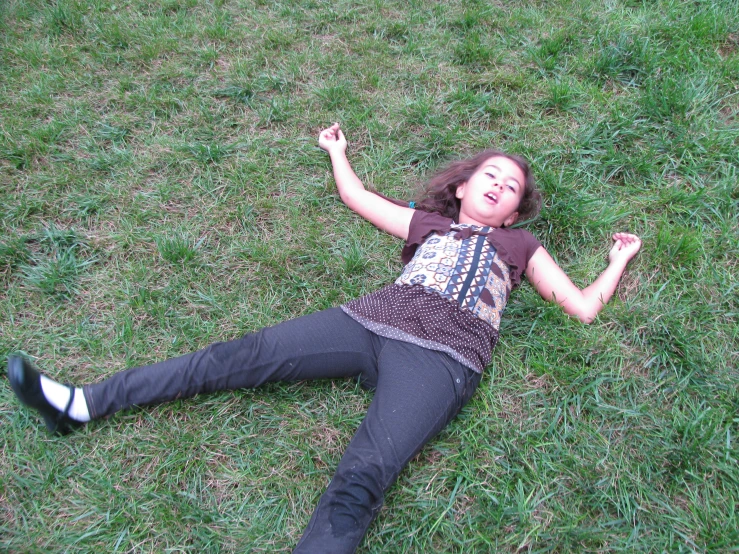 a girl lays in the grass holding her arm up