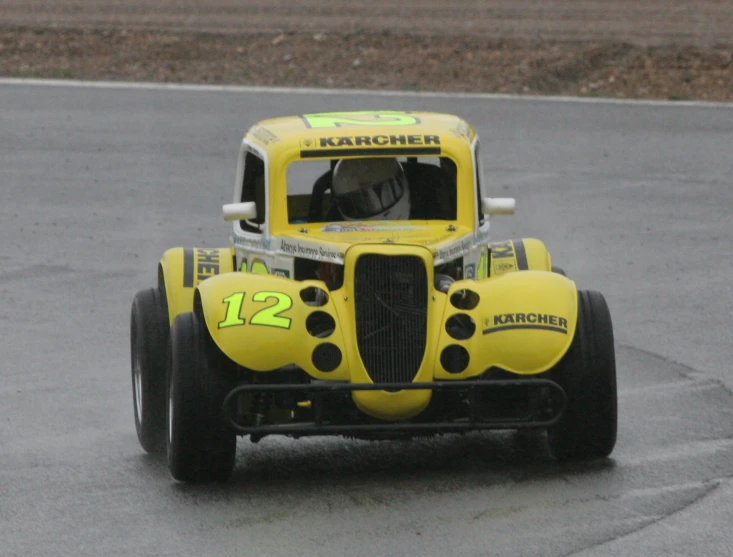 an older model yellow race car in motion