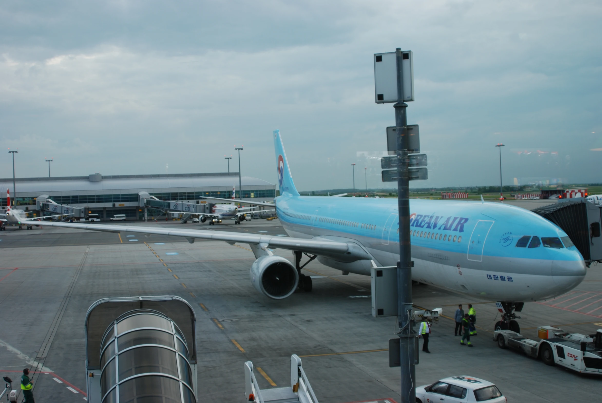 a light blue plane is on the runway and passengers are walking in line