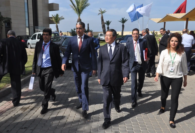 a group of men and women are walking together down the sidewalk