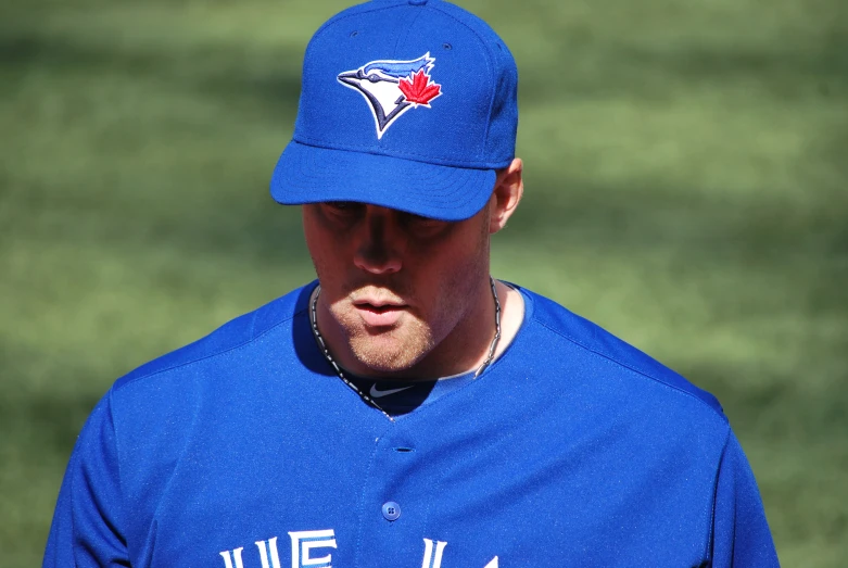 a blue jay baseball player with a red maple leaf on his shirt and hat