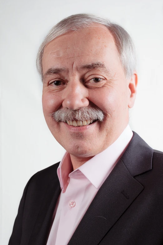 a smiling man with a mustache and pink shirt