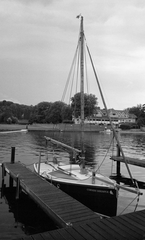 a black and white po shows a sail boat docked on the water