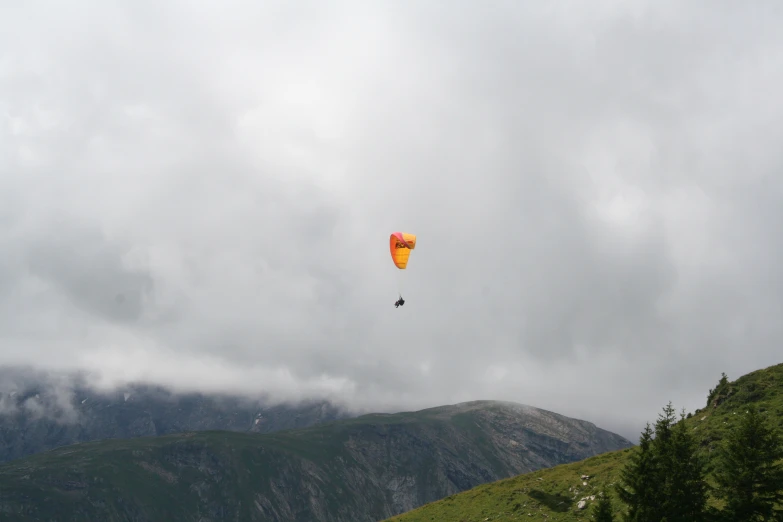 a view from the top of a hill with a person flying a kite