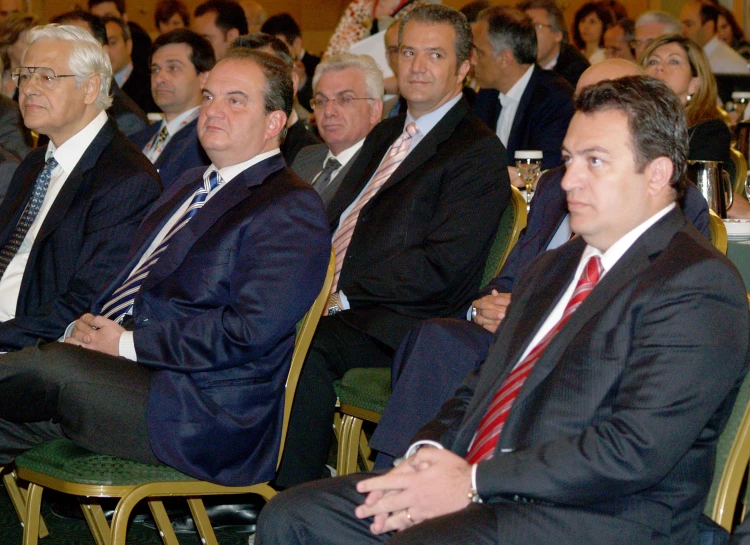 a bunch of people wearing suits sitting down in chairs