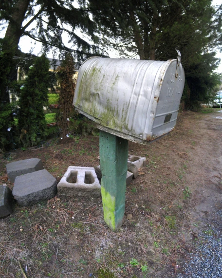 a cement mailbox in a forest with trees behind it