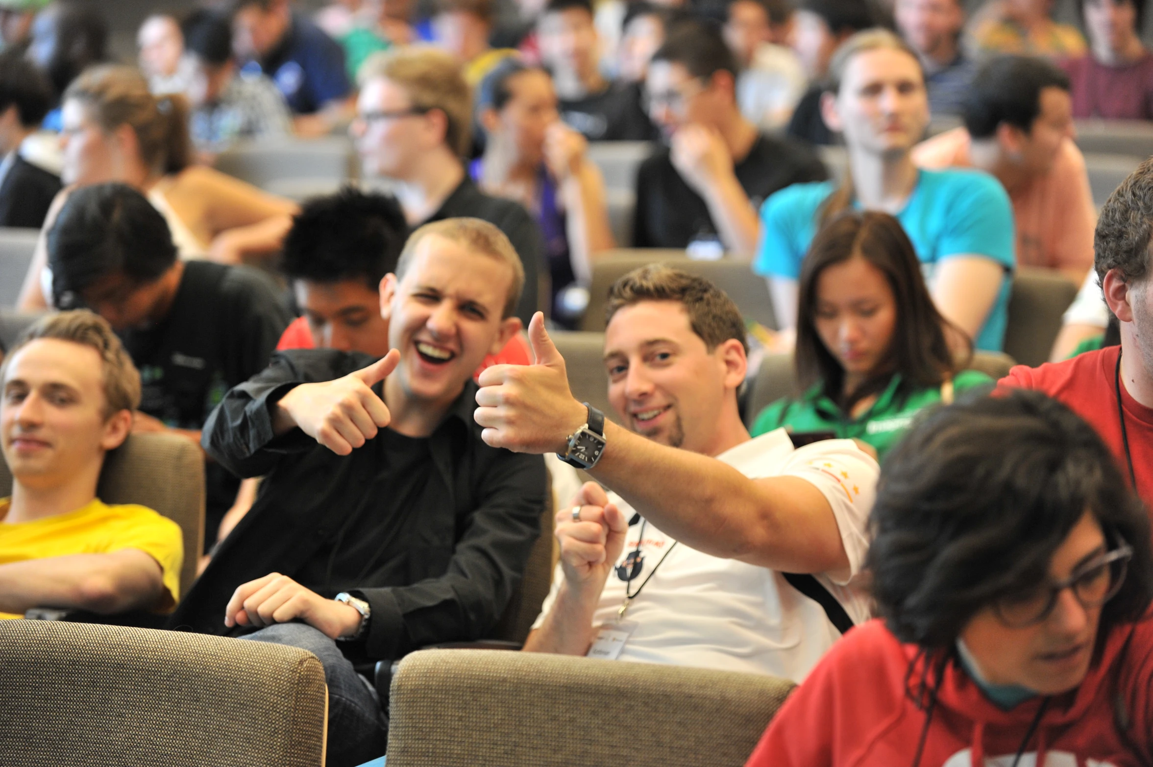 three guys giving the thumbs up sign in a crowd