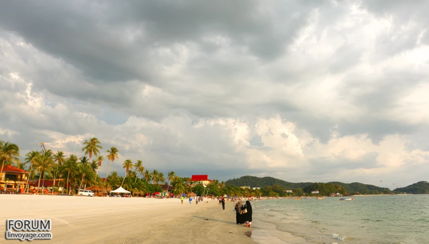 people are walking along the beach in the sun