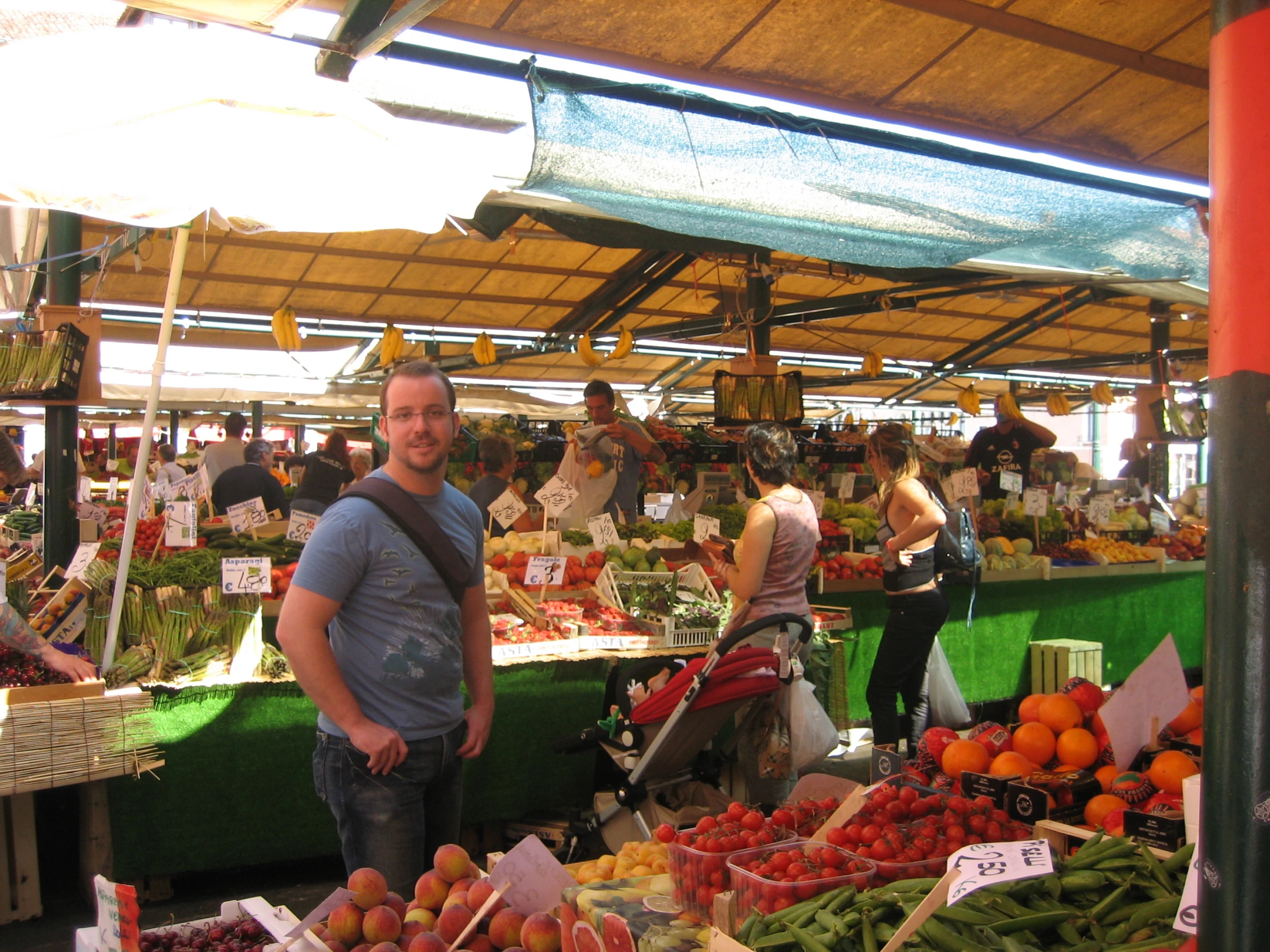 a man at an outdoor farmer's market poses for a picture