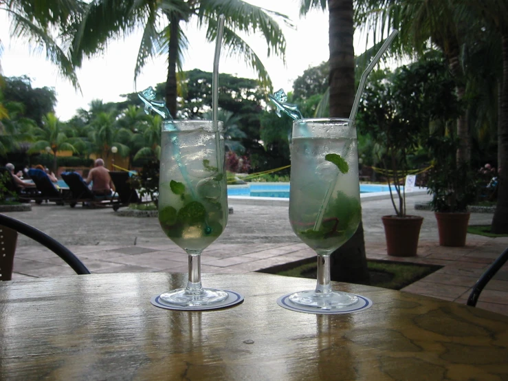 there are two glasses on a table with drinks