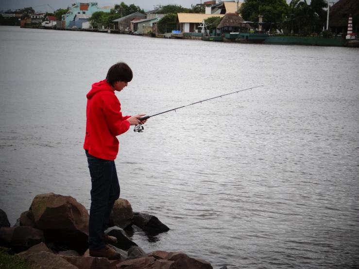 a man stands in the water fishing with a pole