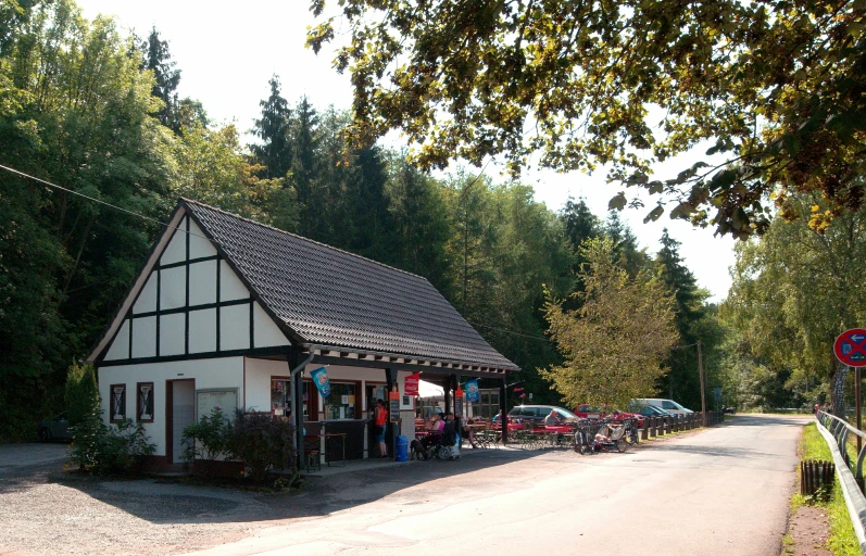 a building with a large roof next to a forest