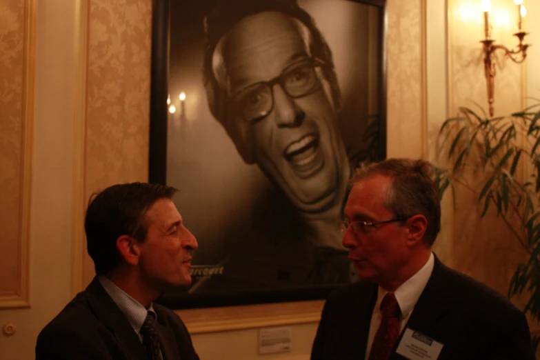 two men with ties are talking in front of an advertit