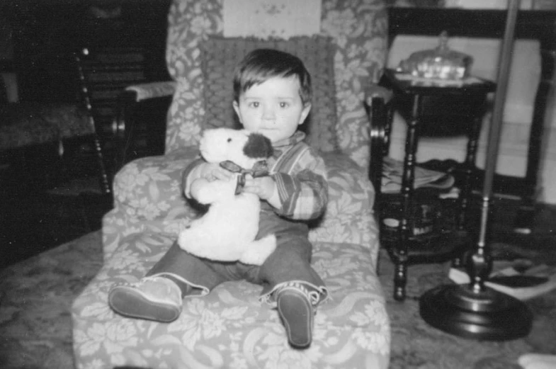 a child sits on a chair and holds a stuffed animal