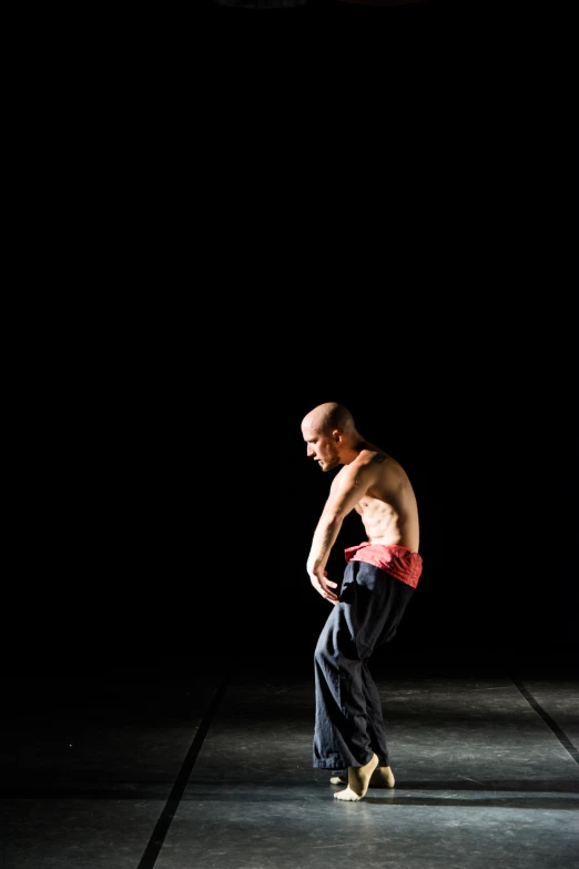 a shirtless man posing for the camera in a dark room