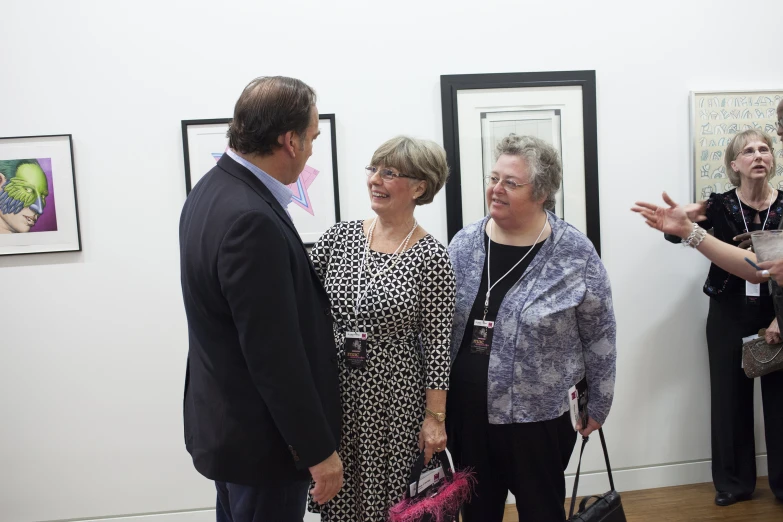 four people talking while looking at the art on display