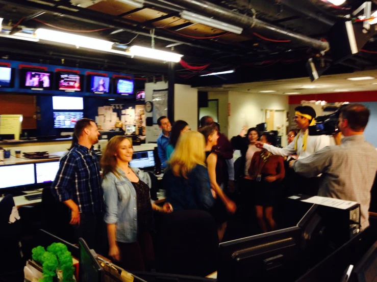 a group of people in an office that is filled with television screens