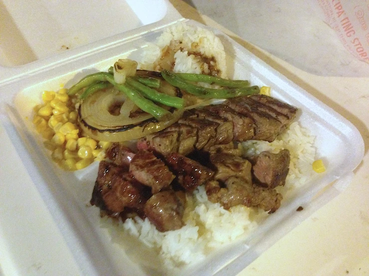 a plastic tray that contains some meat and rice