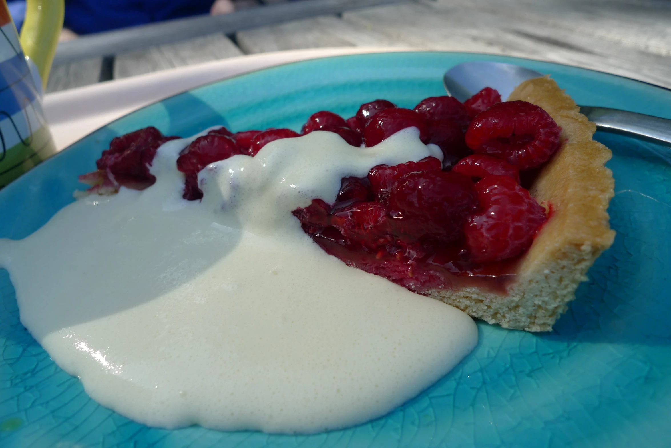 there is a pastry on the plate with raspberries and cream