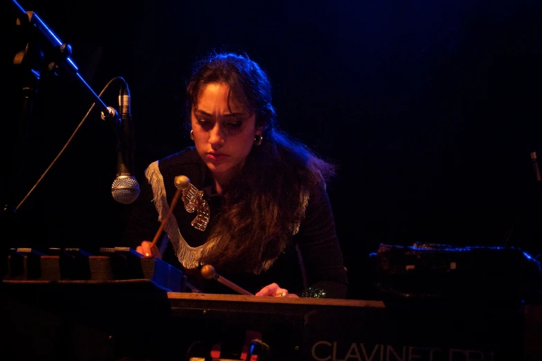 woman with instrument playing keyboard while singing into microphone