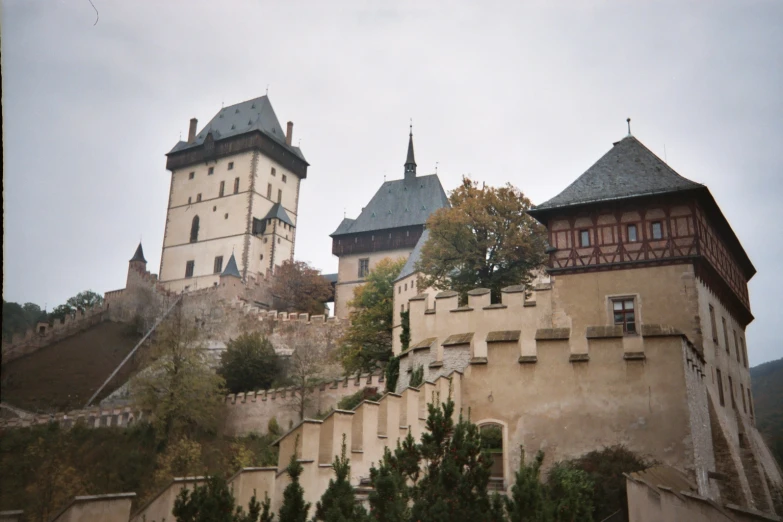 old buildings on a hill next to a tree and mountain