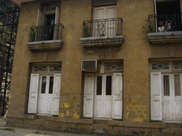 an image of two people sitting in the windows outside a building